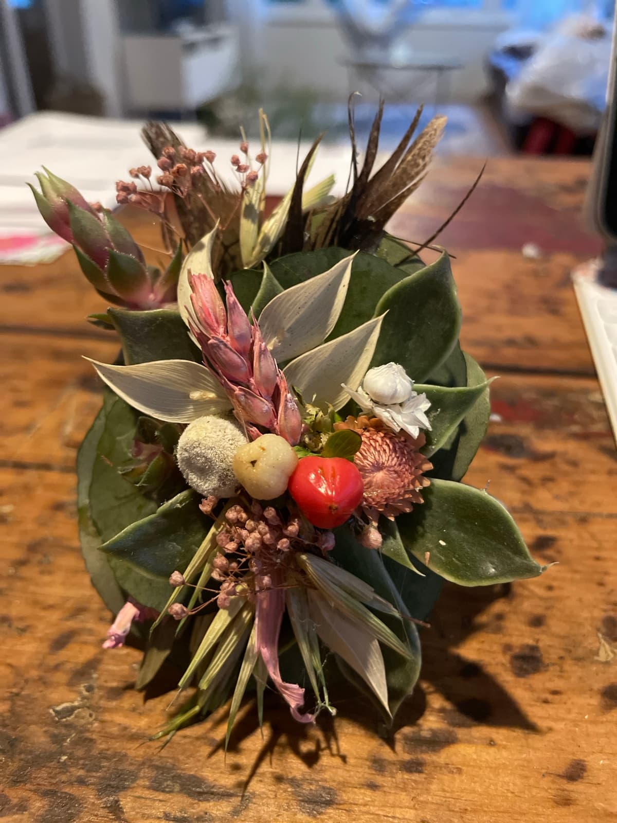 Close-up of a small, rustic corsage with dried flowers and greenery.