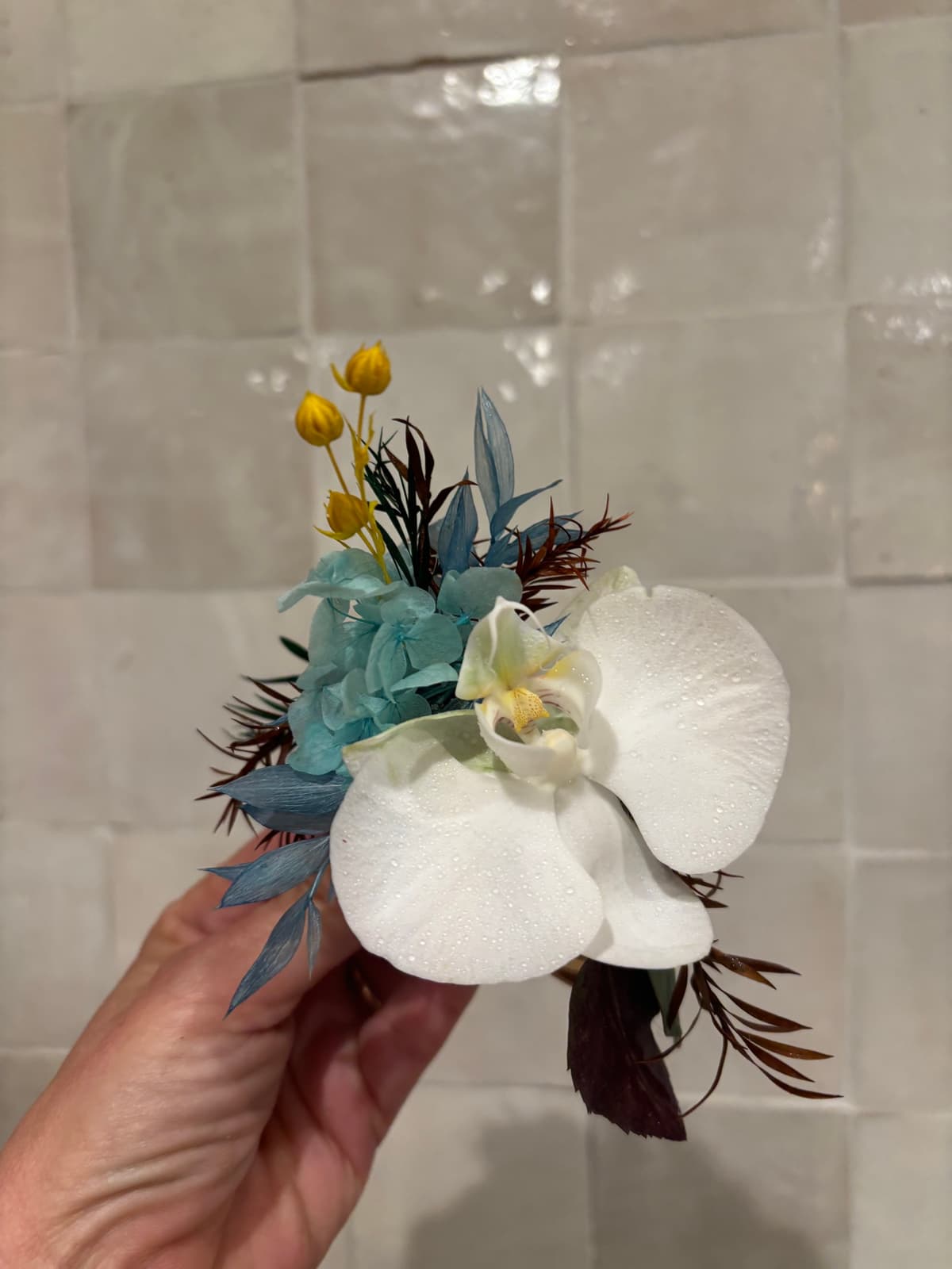 White orchid boutonniere with blue hydrangea and yellow accents