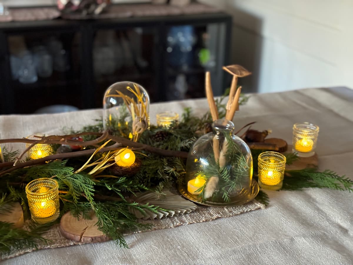 A rustic floral centerpiece with evergreens and candles