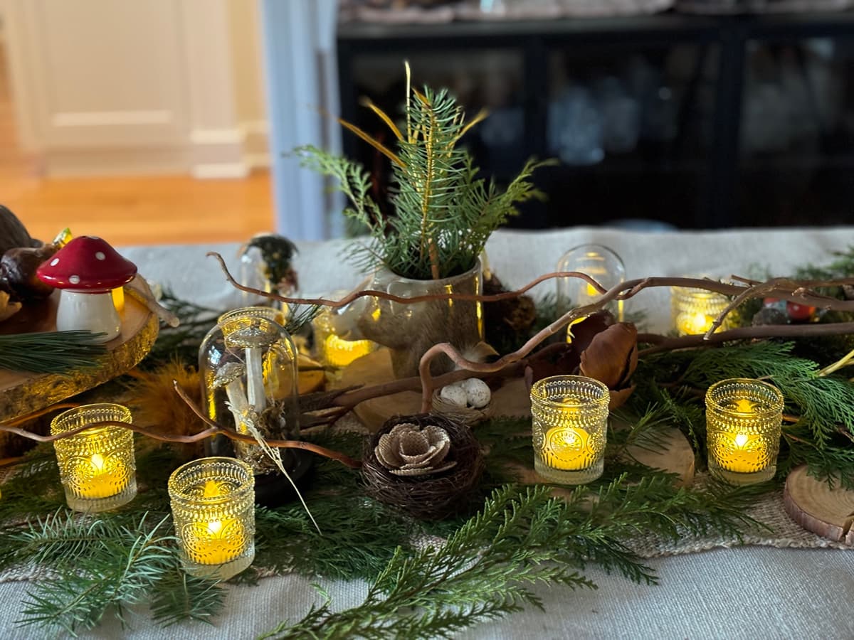Whimsical centerpiece with mushrooms, evergreens, and candles.