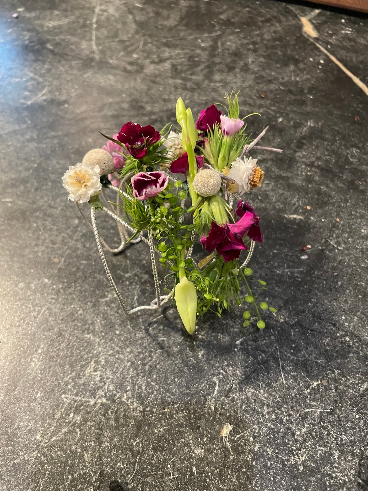 Close-up of a handcrafted floral corsage with burgundy, cream, and pink flowers on a silver wristlet.